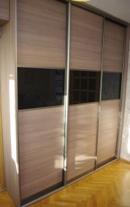 Drzwi przesuwne w szafie na wymiar, połączenie płyty i czarnego szkła lacobel