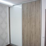 Szafa wnękowa w sypialni, drzwi przesuwne to połączenie białego szkła lacobel i płyty laminowanej