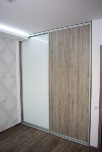Szafa wnękowa w sypialni, drzwi przesuwne to połączenie białego szkła lacobel i płyty laminowanej